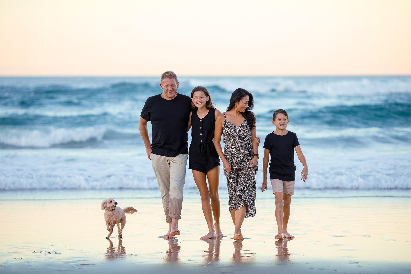 Family walking out of the surf with their small dog