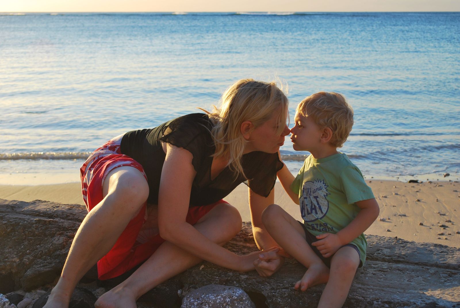 Mom and son touching noses on the rocks