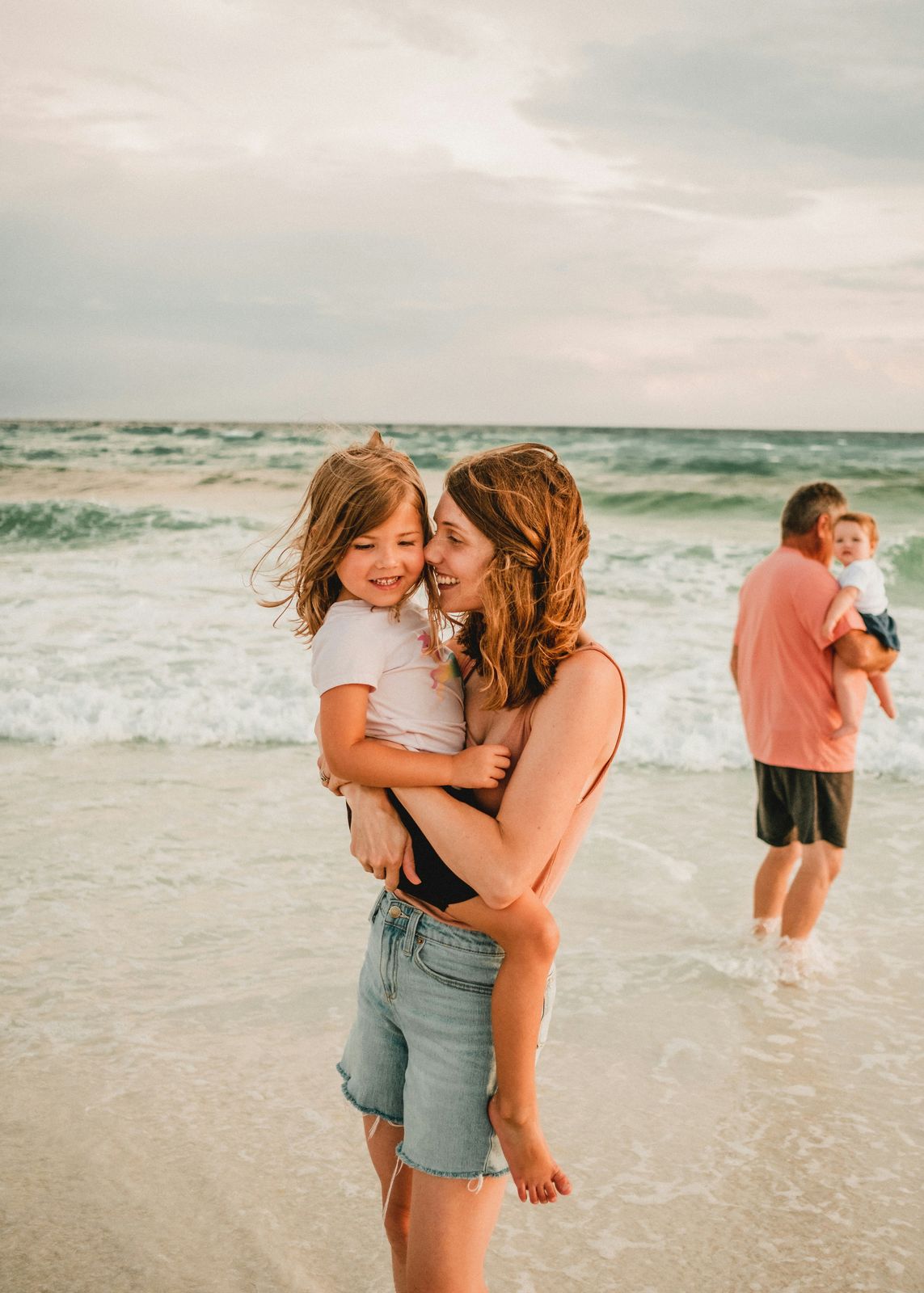 Mom cuddling her daughter in the shallow water