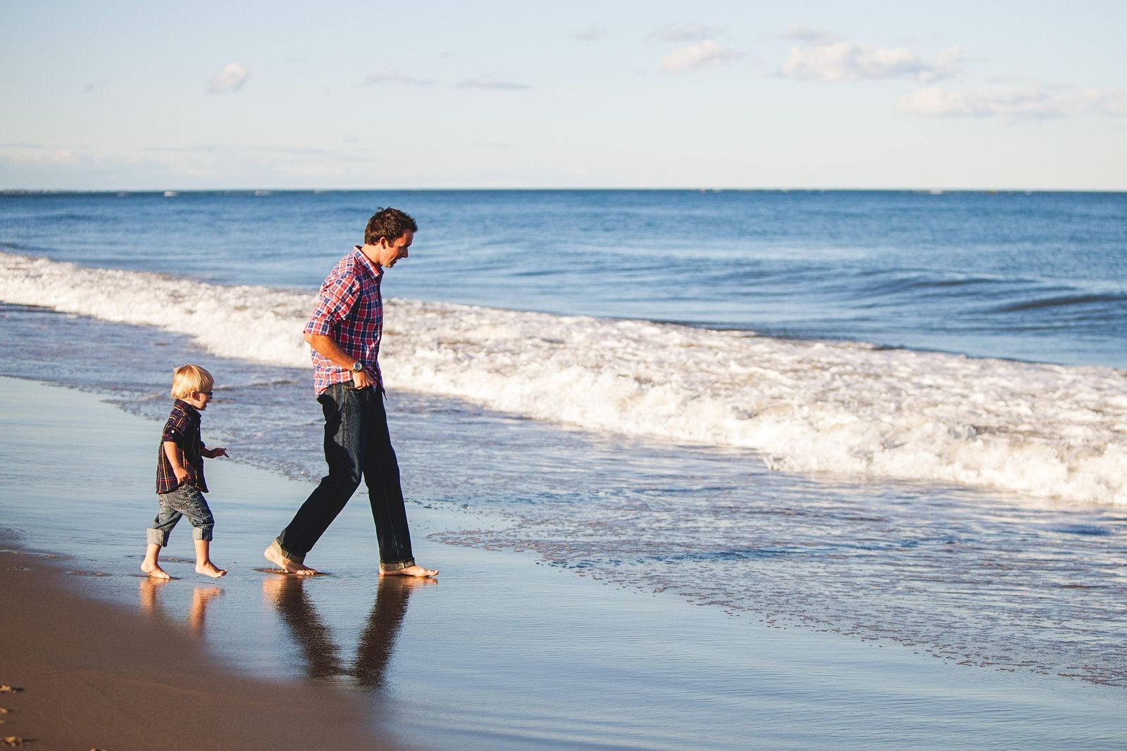 Dad and his little son walking into the waves together
