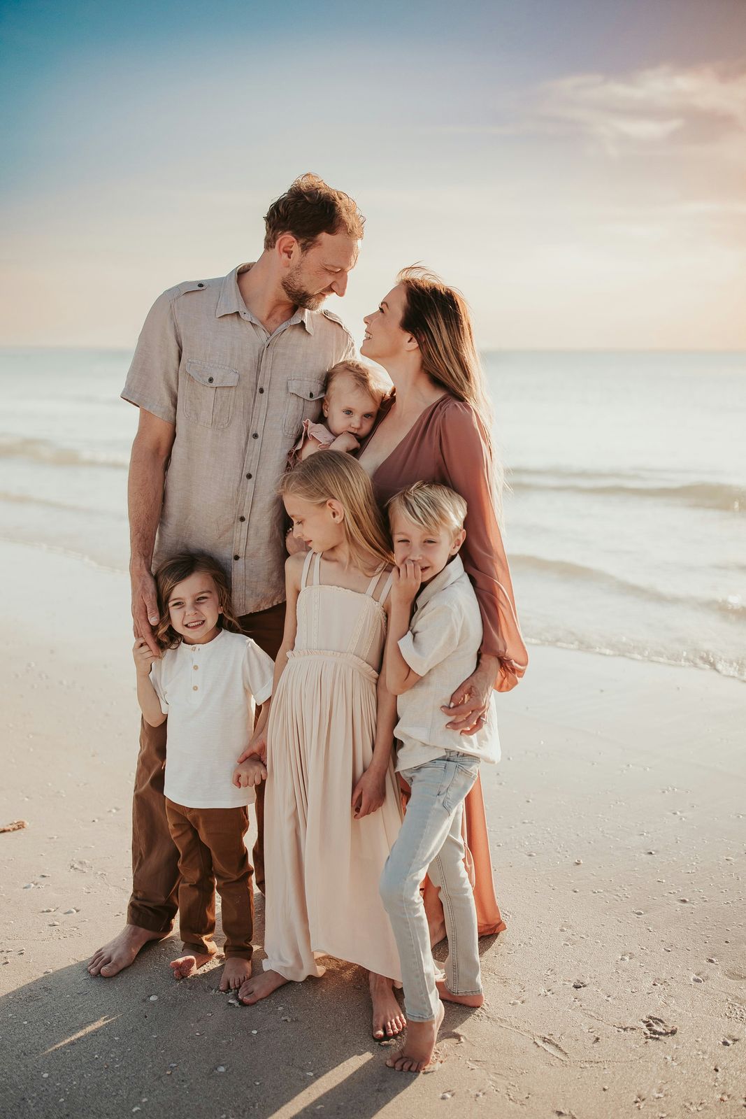 Family of six hugging together on the beach