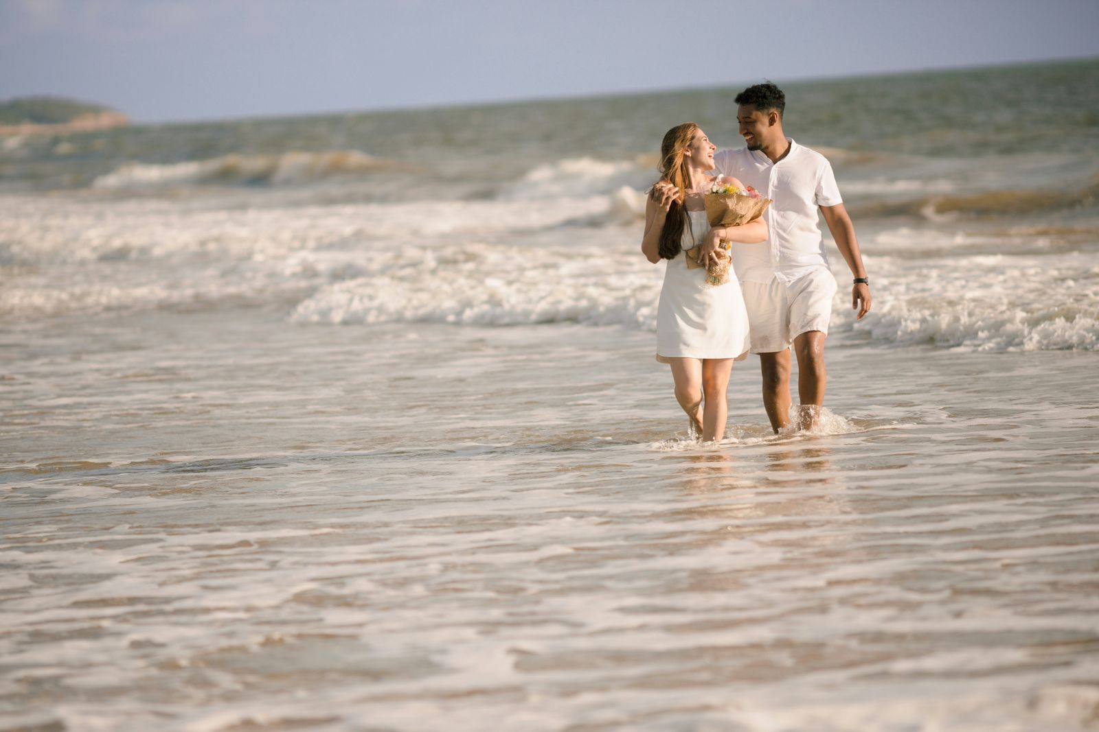 Couple laughing as they walk through the surf