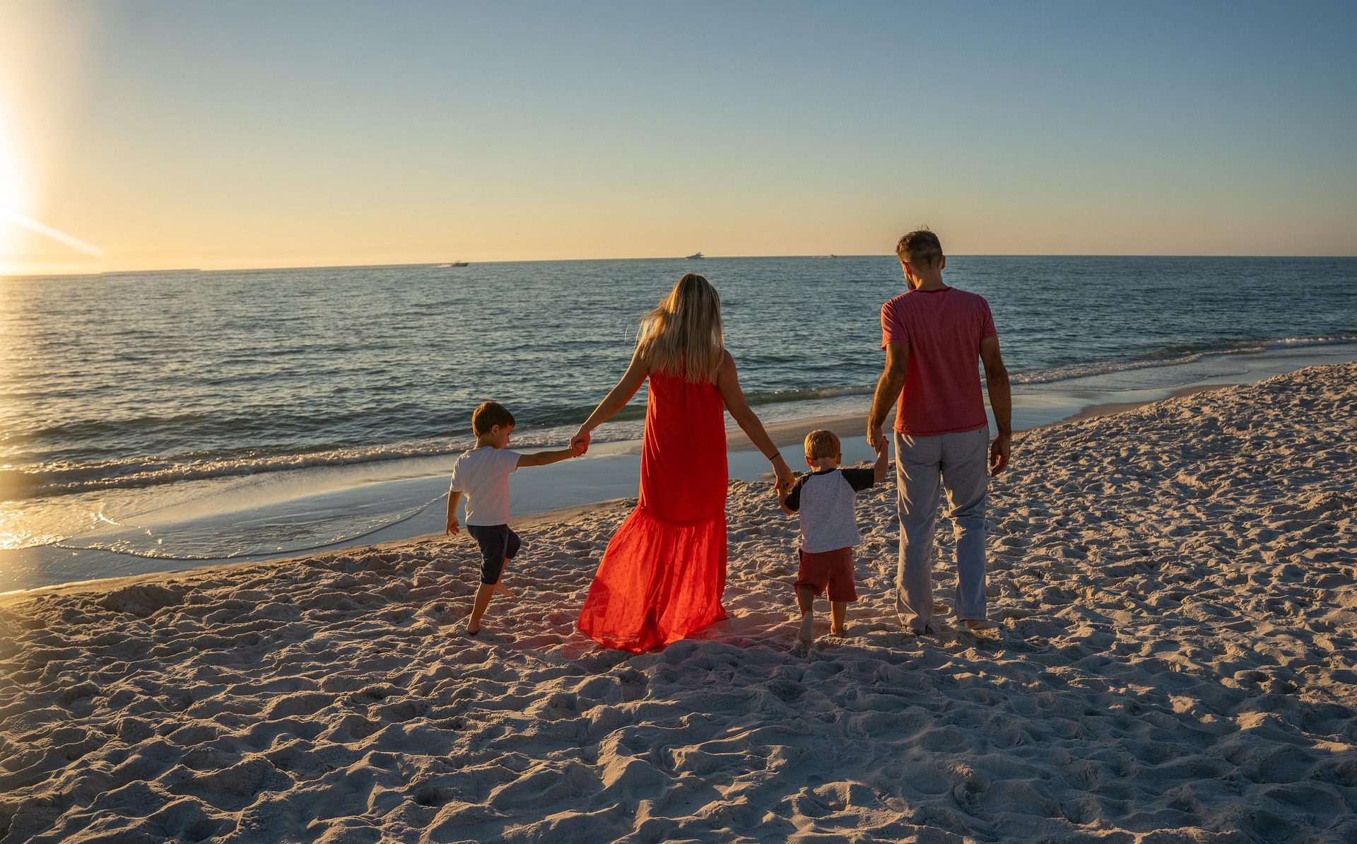 A family walking toward the sunset on the beach